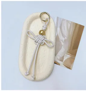 Détails macro d'un pendentif de sac en cuir PU blanc crème tissé à la main.