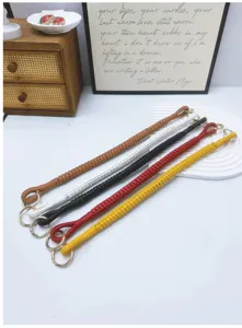Detailed view of five colorful hand-woven PU leather bag handles with gold rings