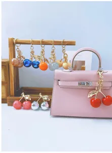Colorful simulation cherry keychains displayed as adorable accessories on a stylish pink handbag
