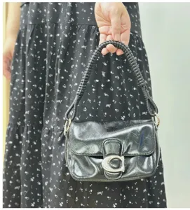Detail of black PU leather handbag featuring a unique hand-braided strap and C-buckle.