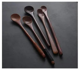 Detail view of five Japanese style long-handled wooden stirring spoons on a dark surface.