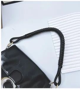 Detail of hand-woven black PU leather strap for handbag with golden ring attachment