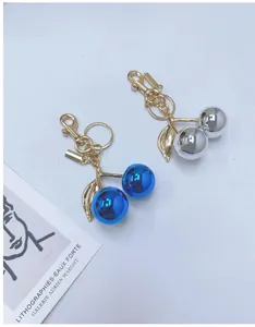 Detailed view of metallic cherry keychains in shiny blue and silver finishes.
