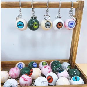 Gothic horror realistic eyeball keychains with heart charms on a wooden display stand