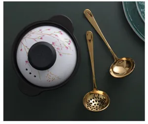 Detail view of 304 stainless steel gold soup ladle and slotted spoon by a ceramic pot