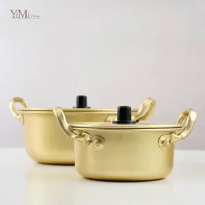 Golden Korean ramen pots in two sizes with lids and double handles on white background