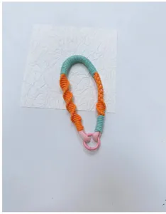 Detailed view of a multi-color hand-braided wrist strap lanyard featuring a pink metal ring