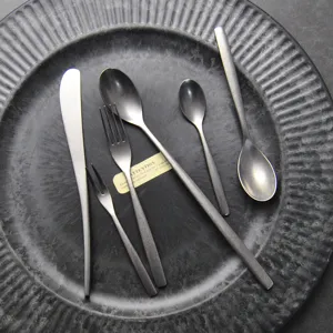 Vintage Besteckset aus mattem silbernem Edelstahl auf einem dunklen Teller präsentiert