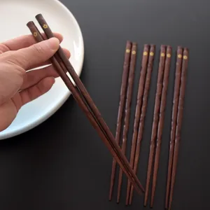 Japanische Essstäbchen aus dunklem Holz mit goldenem Kirschblütenmuster auf Schwarz