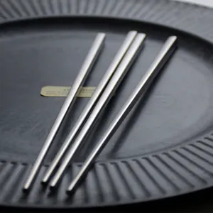 Retro 304 stainless steel chopsticks with non-slip square head design on a black plate