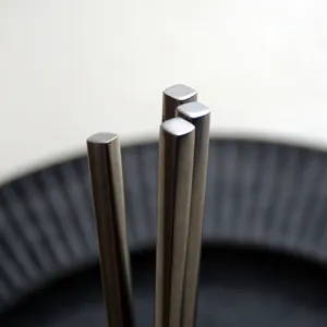 Macro view of vintage 304 stainless steel square-head chopsticks with a distressed finish.