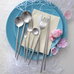 Matte silver stainless steel cutlery set with round handles on blue plates