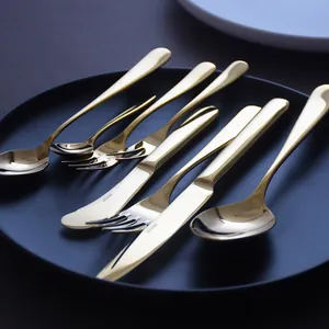 Luxury golden stainless steel cutlery set with knife, fork, and spoon on a black plate