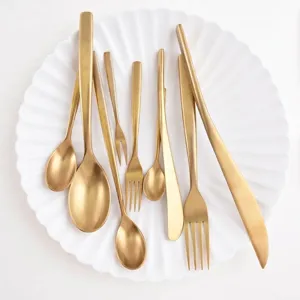 Elegant gold matte stainless steel flatware set displayed on decorative white plate