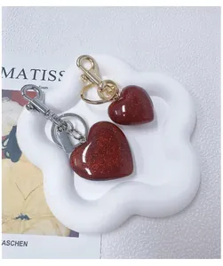 Close-up of sparkling dark red glitter heart keychain with gold and silver hardware