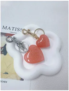 Close-up of glittery heart keychains in gold and silver finish on a decorative tray