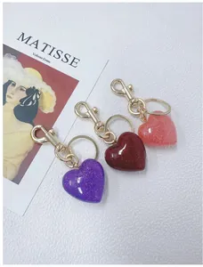 Detailed view of three heart-shaped glitter keychains in purple, red, and pink colors.