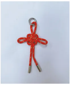 Detail shot of red braided rope keychain with gold metallic thread and metal tips