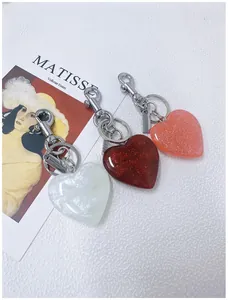 Detail view of sparkly glitter and marbled heart-shaped keychains on artistic background