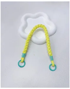 Close-up detail of handmade braided phone wrist strap in vibrant yellow with teal rings