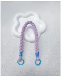 Detailed view of a purple handmade braided phone wrist strap displayed on a floral tray.
