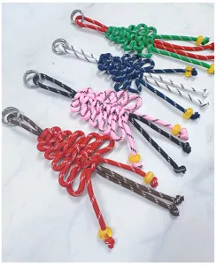 Quattro ciondoli a forma di albero di Natale in paracord intrecciato a mano in rosso e rosa.