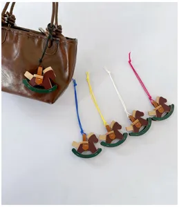 Handmade rocking horse bag charms in various colors shown as a detail on a bag.