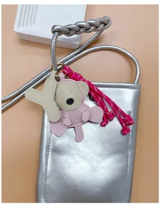 Close-up of a cute pink PU leather monkey charm with a Y-letter pendant on a bag.