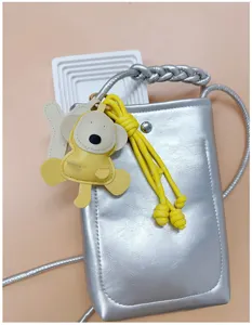 Close-up of a cute yellow handmade PU monkey bag charm with a thick woven yellow lanyard