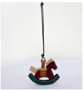 Close-up of a handmade leather rocking horse bag charm with dark red and green accents.