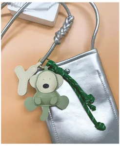 Detail of a handmade green PU monkey keychain on a metallic silver crossbody bag