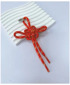 Hand-woven red cord knot charm with gold flecks on white wavy decorative display