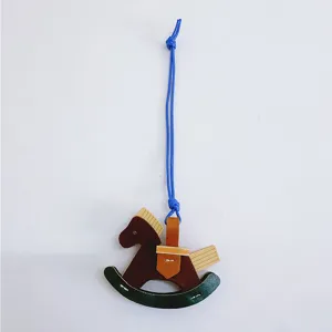 Detailed view of handmade leather and wood rocking horse bag charm with blue hanging string