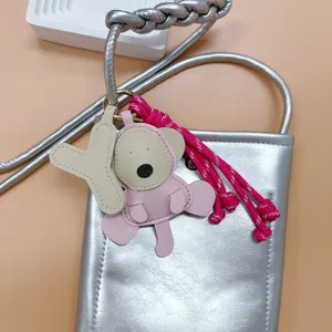 Handmade PU leather cartoon monkey keychain charm with pink tassel on a silver bag.