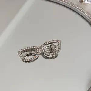 Detailed view of an elegant silver hair clip shaped like spectacles with rhinestones