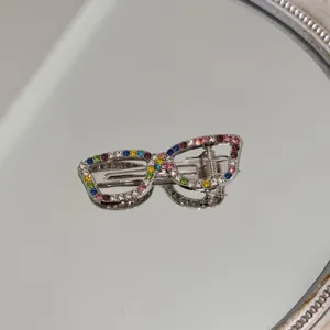 Close-up macro view of a silver rhinestone eyeglasses hair clip with colorful crystals
