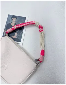 Nahaufnahme des handgeflochtenen rosa Seilgriffs an einer cremefarbenen Tasche