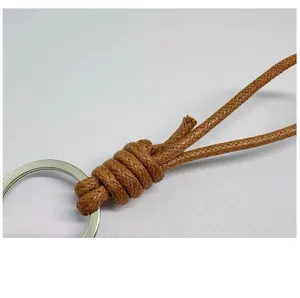 Detail macro shot of handmade braided brown wax rope knot on a silver keychain ring