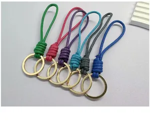 Detailed close-up showing six colorful handmade braided wax rope keychains with gold rings