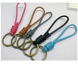 Detail of five handmade woven wax rope keychains in various colors with metal rings