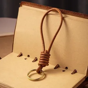 Portachiavi artigianale in pelle marrone con anello d'oro su taccuino vintage