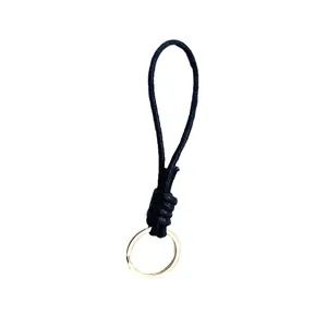 Hand-braided black wax rope keychain with gold ring, minimalist wrist strap pendant.