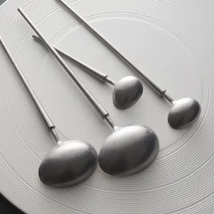Cucharas vintage japonesas de acero inoxidable con mango largo sobre un plato blanco