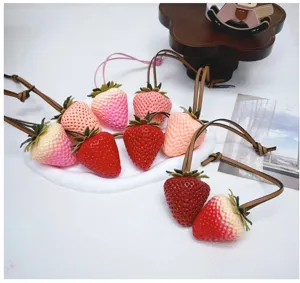 Detailed view of 3D simulation strawberry bag charms with leather straps in various colors