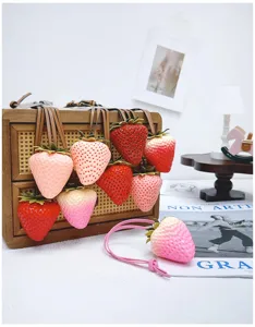 Close-up of realistic 3D strawberry bag charms in various shades of pink and red.