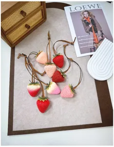Detailed view of realistic large 3D strawberry bag charms with leather straps in red