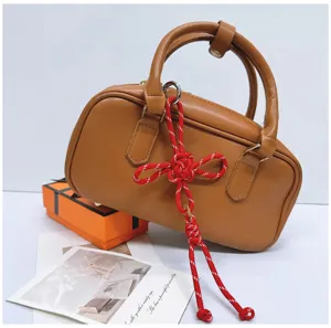 Detailed view of a red handmade braided Chinese knot charm accessory on a leather bag