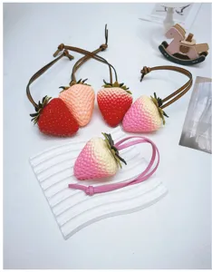 Detailed view of realistic strawberry bag charms in various colors with leather straps