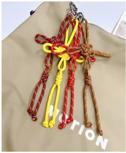 Detailed view of four colorful hand-woven Chinese knot charms on a khaki tote bag