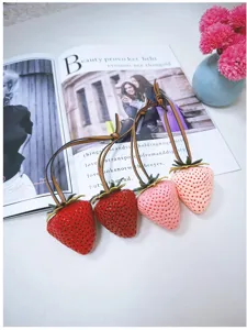 Detailed macro shot of four realistic 3D strawberry bag charms in various pink and red shades